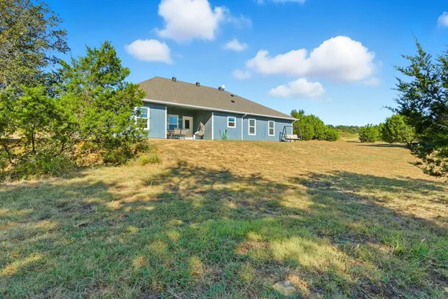 a view of an house with backyard and a tree