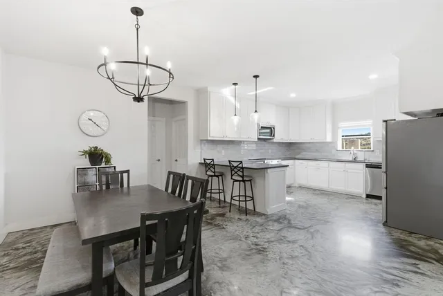 a kitchen with stainless steel appliances granite countertop a dining table chairs and white cabinets