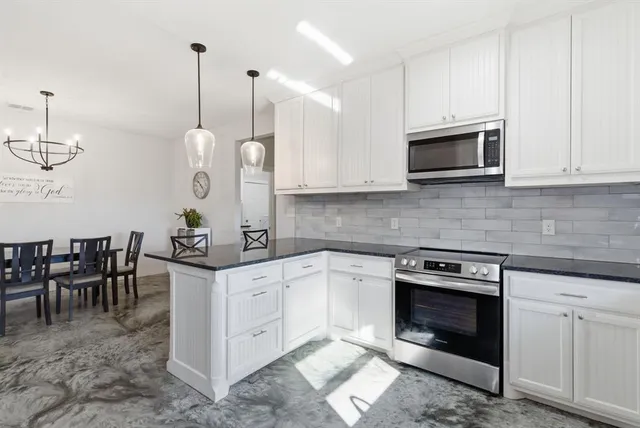 a kitchen with stainless steel appliances granite countertop a stove a sink and white cabinets