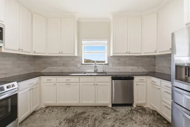 a kitchen with granite countertop white cabinets and stainless steel appliances