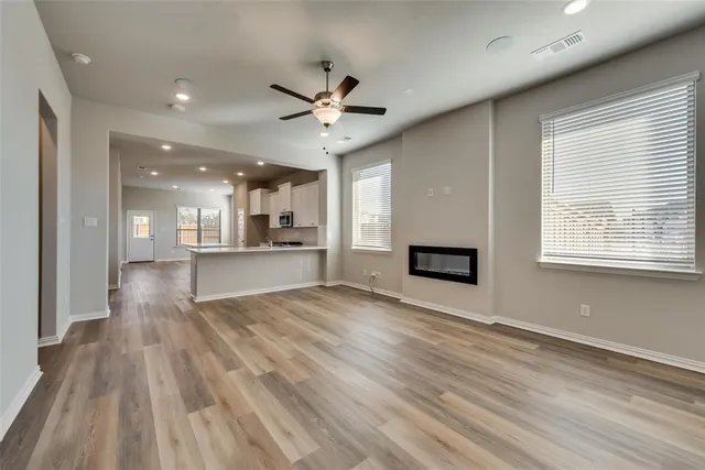 a view of an empty room with a kitchen and a window