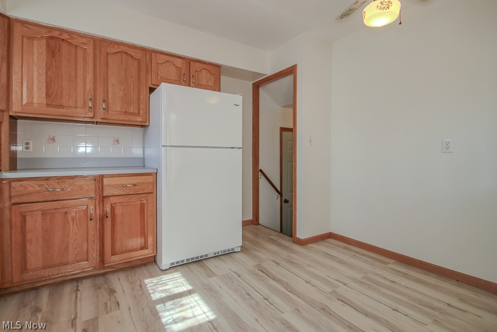 30224 Regent Road Wickliffe, OH 44092 - Photo 6 of 27 Kitchen with light countertops, freestanding refrigerator, wood finish cabinets, light wood-style flooring, and tasteful backsplash
