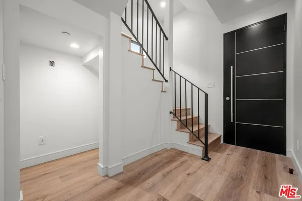 a view of an empty room with wooden floor and stairs