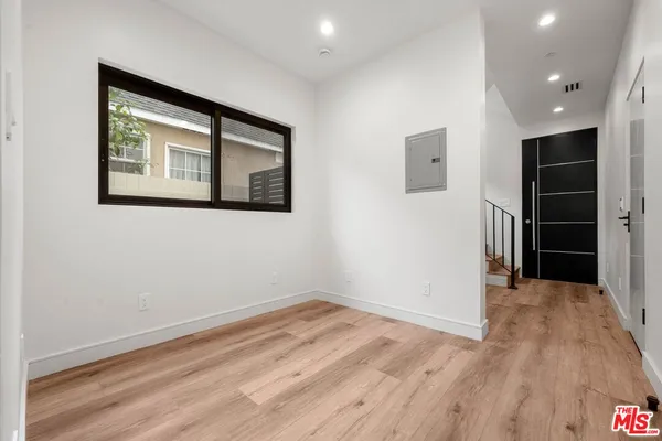 a view of an empty room with a window and a kitchen