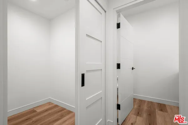 a view of an empty room with wooden floor and closet