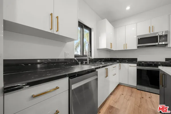 a kitchen with granite countertop a sink and stainless steel appliances