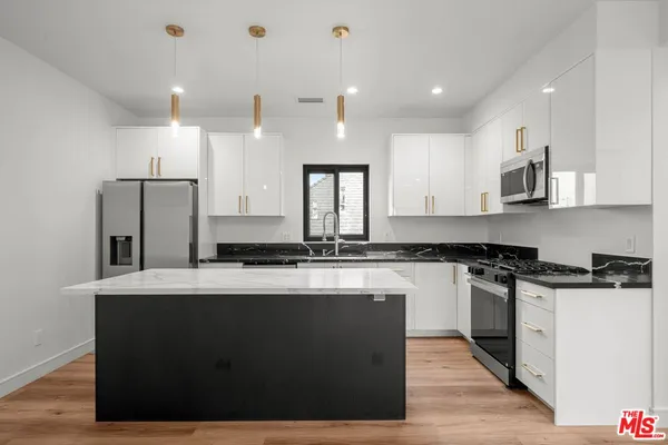 a modern kitchen with stainless steel appliances granite countertop a sink a stove and a refrigerator