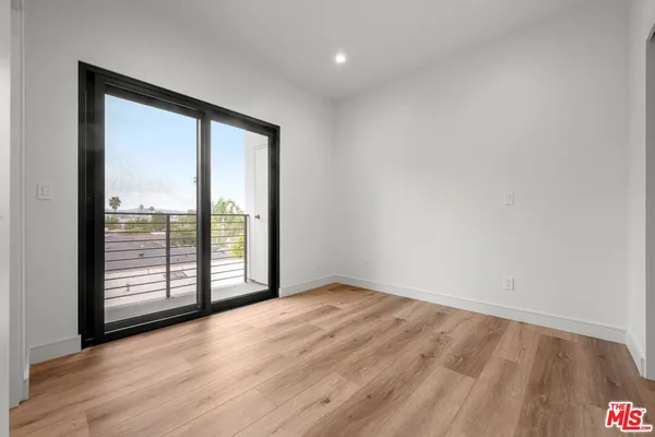 a view of an empty room with wooden floor & closet