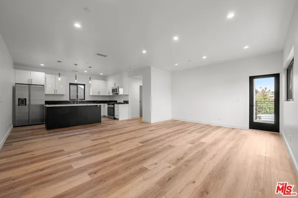 a view of kitchen with kitchen island wooden floor center island and stainless steel appliances
