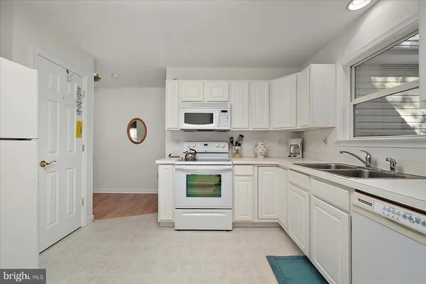 a kitchen with granite countertop white cabinets and white appliances