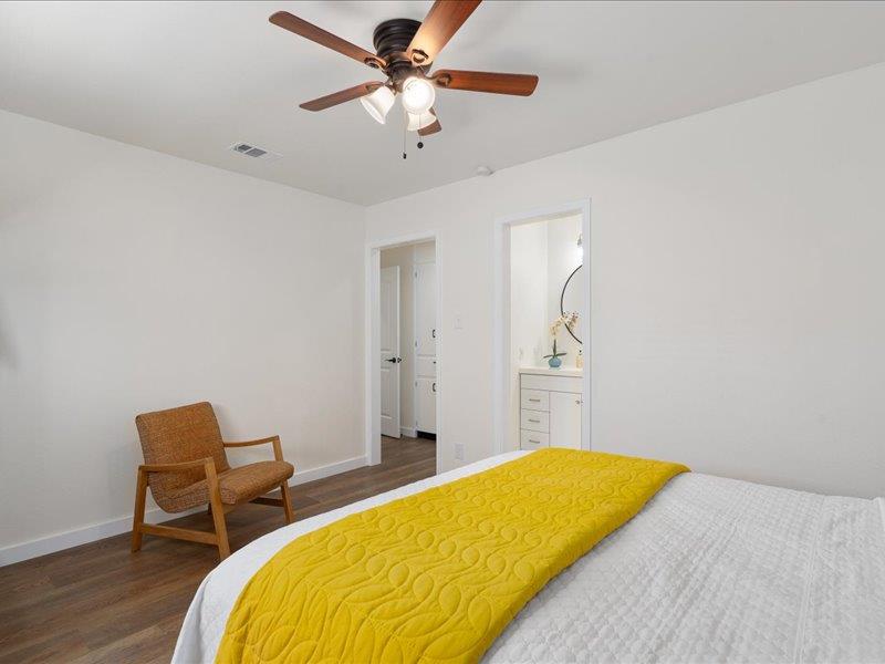 1312 Hyman Lane Austin, TX 78742 - Photo 22 of 36 The property features wood-style flooring, a ceiling fan with integrated lighting, and a white vanity with a circular mirror in an adjoining space