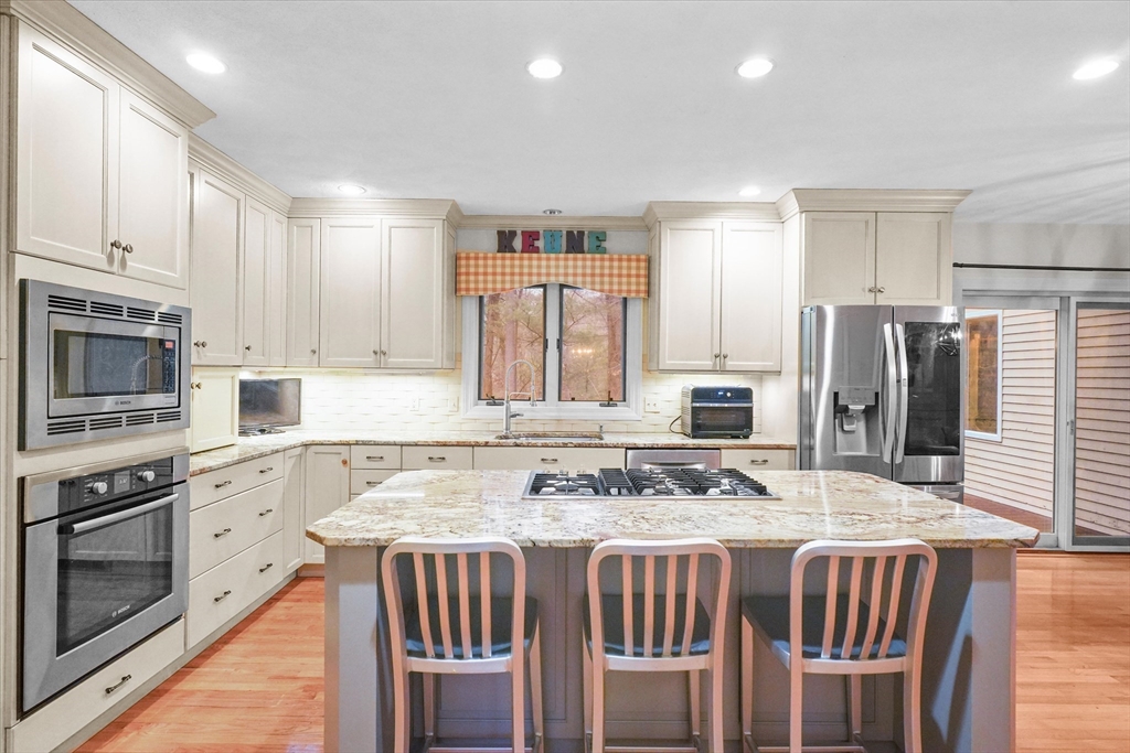 20 Barnside Road Boxford, MA 01921 - Photo 3 of 42 a kitchen with stainless steel appliances granite countertop a stove top oven a refrigerator a sink and a dining table with wooden floor