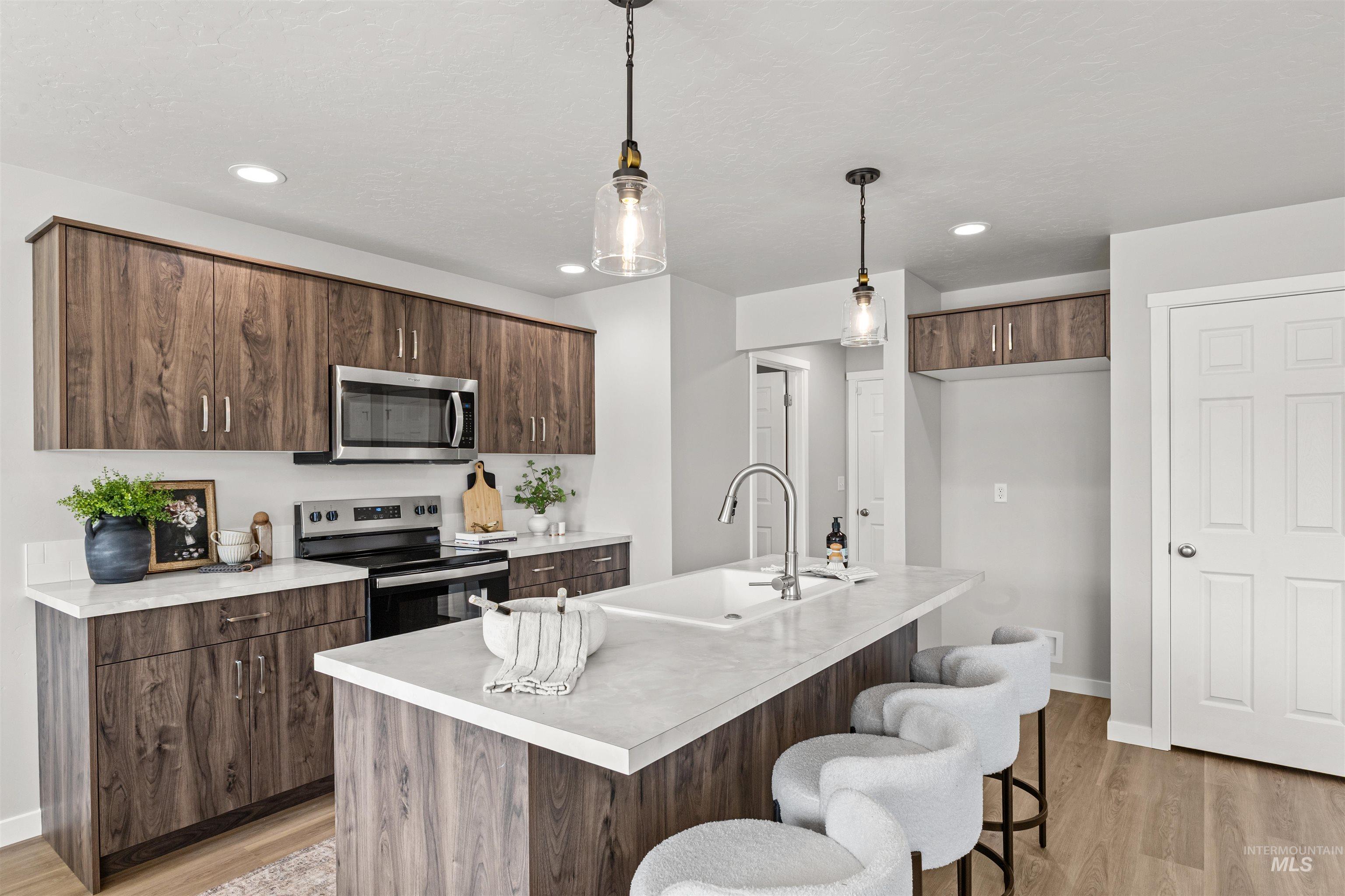 2534 West Fallon Loop Nampa, ID 83651 - Photo 11 of 28 Kitchen with light countertops, stainless steel appliances, decorative light fixtures, a kitchen breakfast bar, and light wood-style flooring