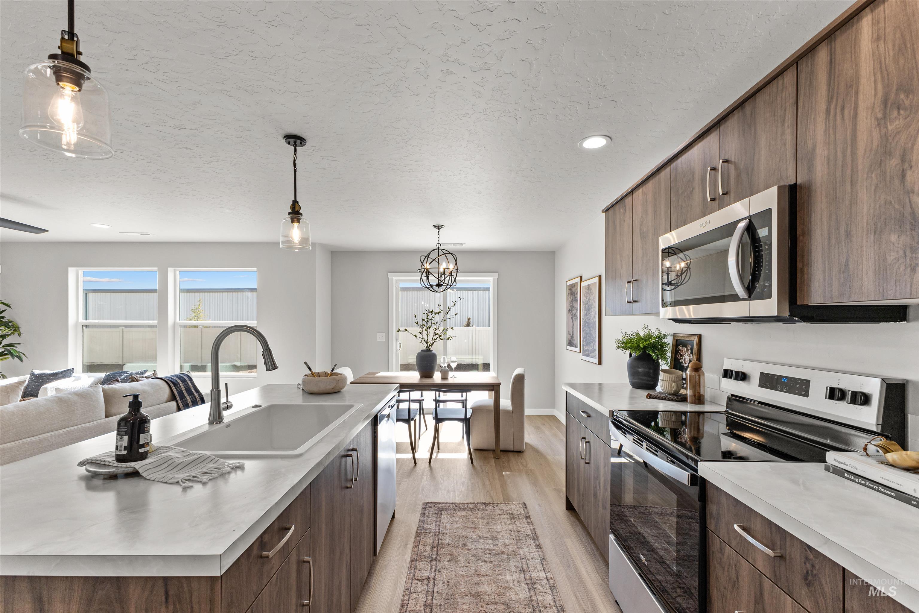 2534 West Fallon Loop Nampa, ID 83651 - Photo 28 of 28 Kitchen with stainless steel appliances, dark wood finish cabinetry, open floor plan, modern cabinets, and a textured ceiling
