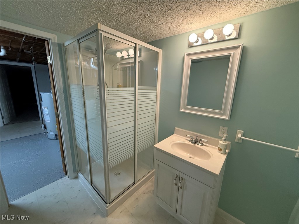 6290 Crossview Road Independence, OH 44131 - Photo 18 of 24 Bathroom featuring water heater, vanity, a shower with door, and a textured ceiling