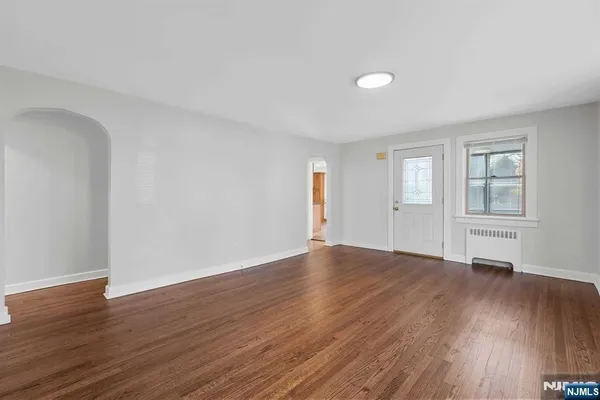 a view of an empty room with window and wooden floor