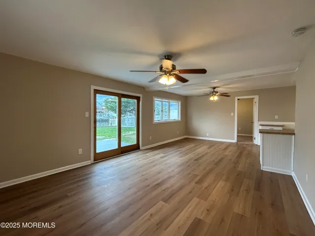 a kitchen with granite countertop a stove top oven a sink dishwasher and white cabinets with wooden floor