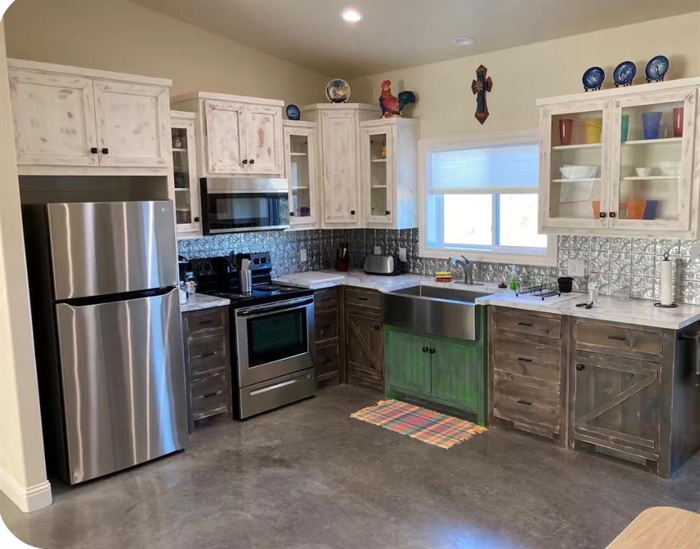 7565 Fm 3116 Anson, TX 79501 - Photo 4 of 15 Kitchen featuring a stainless steel farmhouse sink, pressed tin backsplash, distressed white upper cabinetry, and rustic wood-finish lower cabinetry