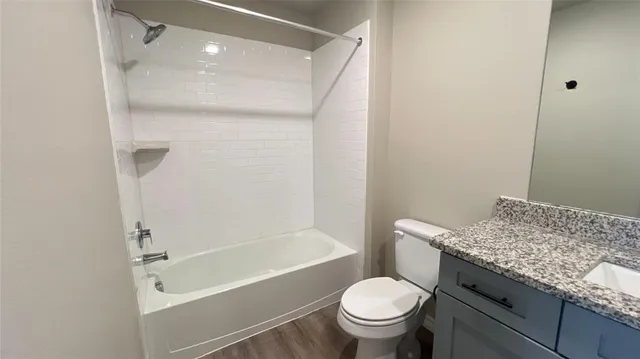a bathroom with a granite countertop toilet sink and mirror