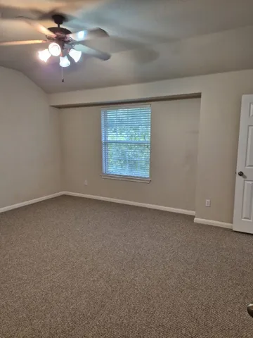 an empty room with a chandelier fan and windows