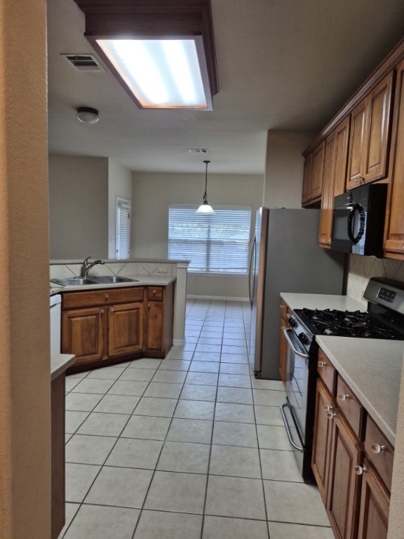 808 Busleigh Castle Way Pflugerville, TX 78660 - Photo 7 of 30 a kitchen with stainless steel appliances granite countertop a stove a sink and a microwave