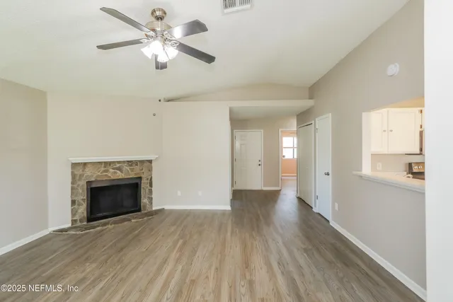 a view of an empty room with chandelier fan and fire place