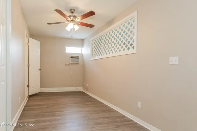an empty room with wooden floor ceiling fan