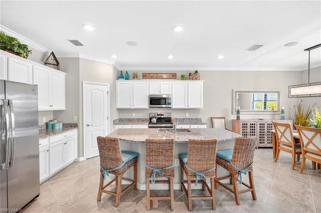 a kitchen with stainless steel appliances kitchen island granite countertop a dining table chairs and refrigerator