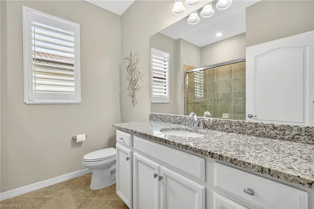a bathroom with a granite countertop sink a toilet and mirror