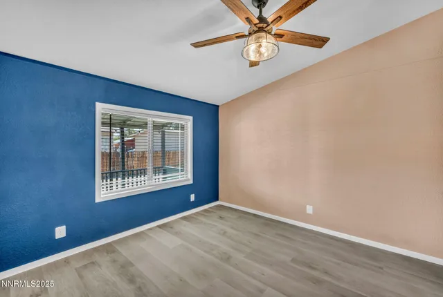 an empty room with wooden floor front door and a ceiling fan