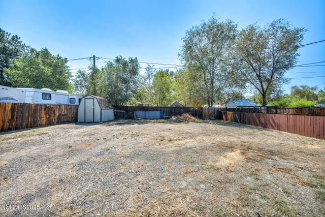 a view of a small house with wooden fence next to a yard
