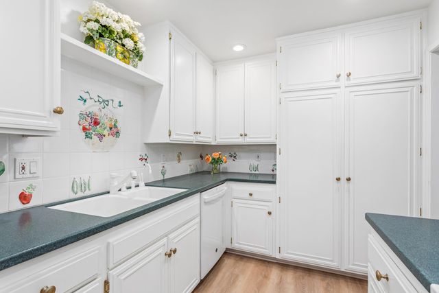 a kitchen with white cabinets and sink