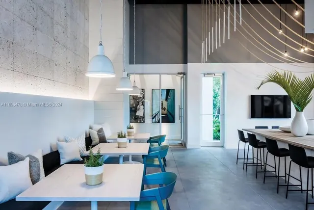 a room with lots of tables a large window and chairs