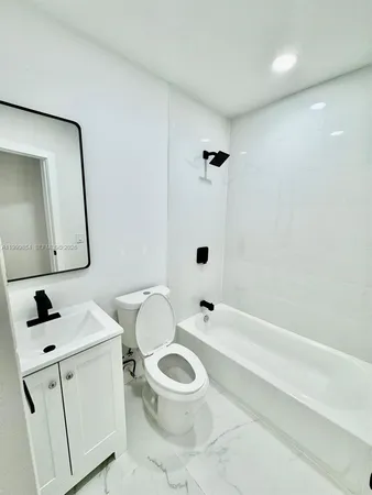 a bathroom with a toilet a sink a mirror and bathtub