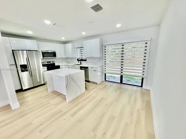 a view of a kitchen with wooden floor and electronic appliances