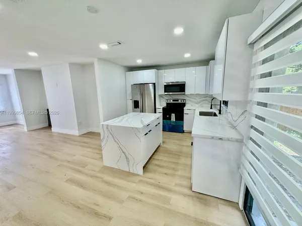 a large white kitchen with white cabinets and stainless steel appliances