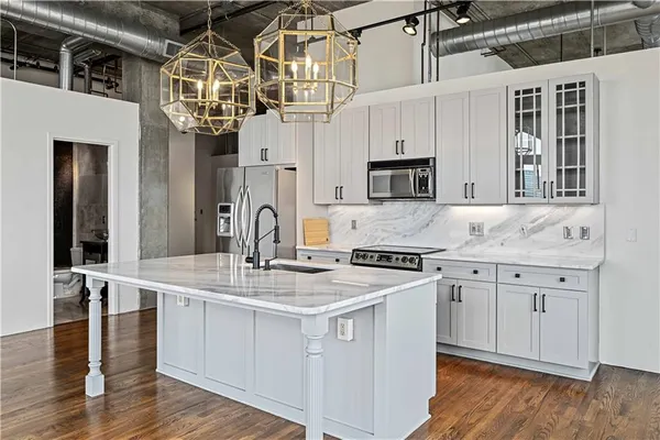 a kitchen with stainless steel appliances granite countertop a sink a stove and wooden floor