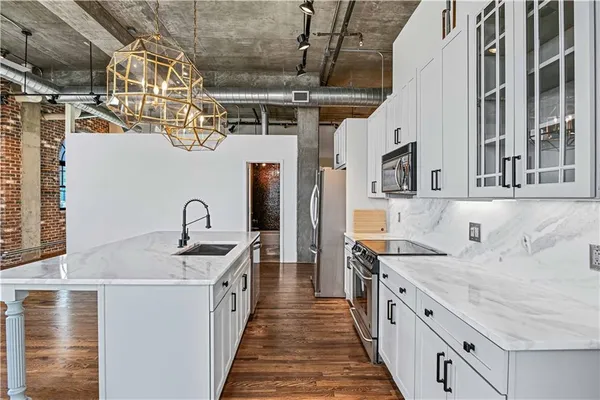 a view of a kitchen with stainless steel appliances granite countertop a sink and cabinets