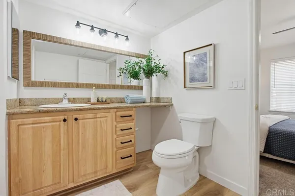 a bathroom with a granite countertop sink toilet and mirror