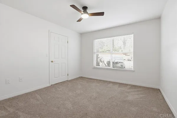 an empty room with a window and a ceiling fan