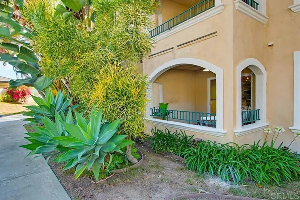 a view of a brick house with plants and large tree