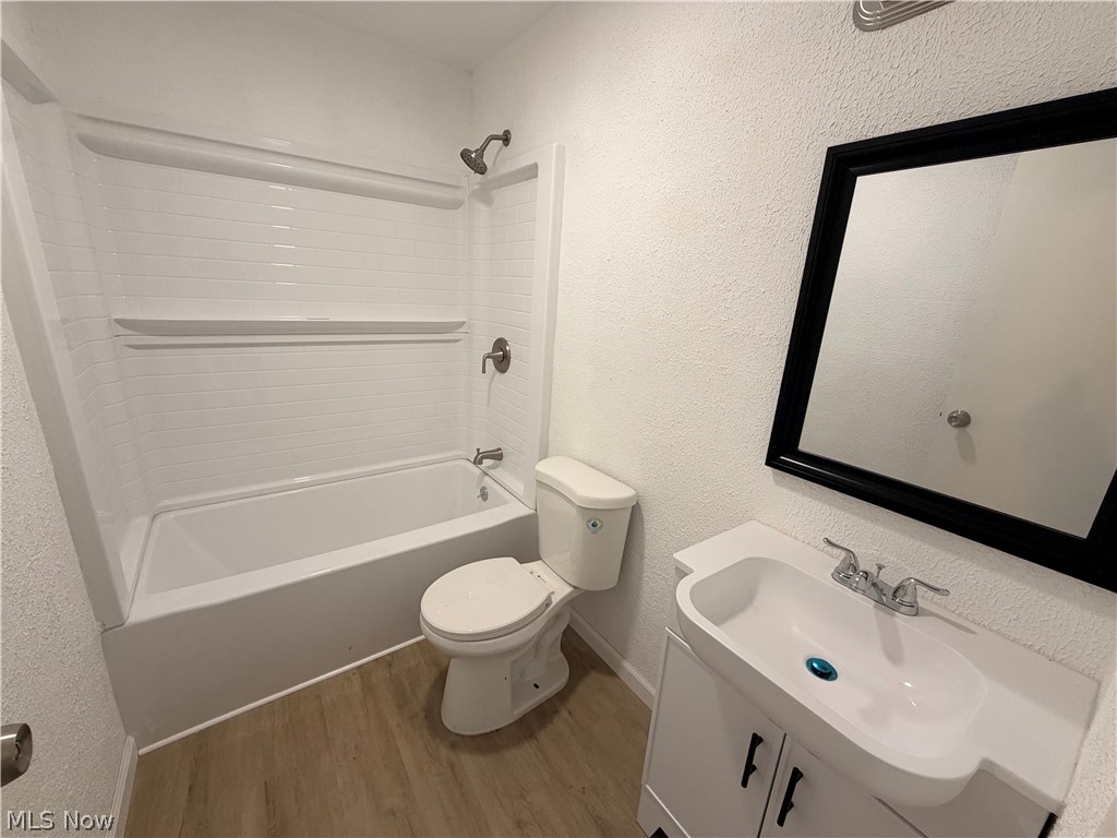693 Liberty Road Youngstown, OH 44505 - Photo 7 of 14 Wood-finish flooring, white vanity with black hardware, white countertop with integrated sink, framed mirror, and a white tiled shower/tub combination