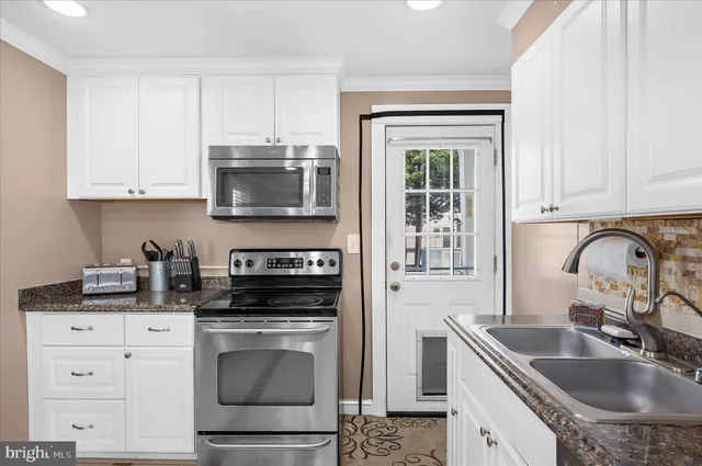 a kitchen with granite countertop a sink stove and cabinets