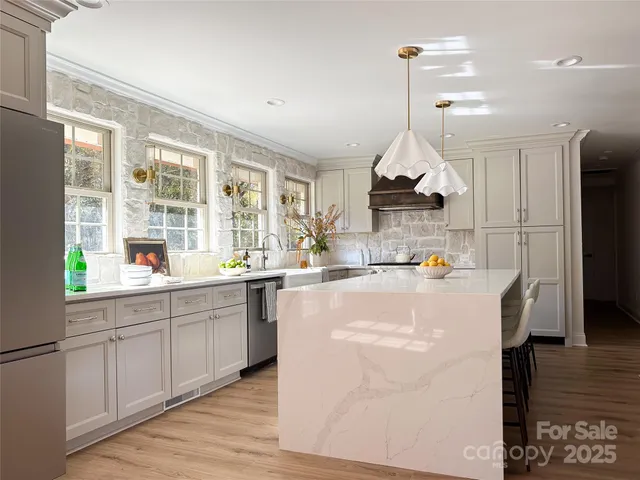 a kitchen with kitchen island granite countertop a stove a sink a refrigerator and a dining table with wooden floor