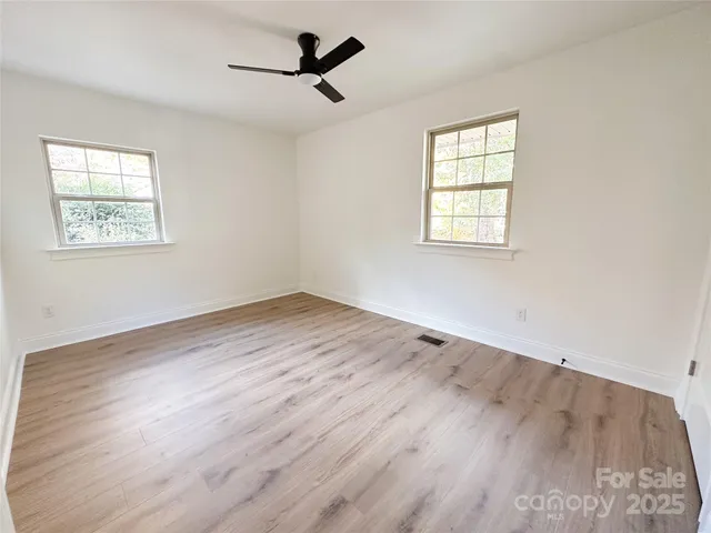 a view of empty room with wooden floor and fan