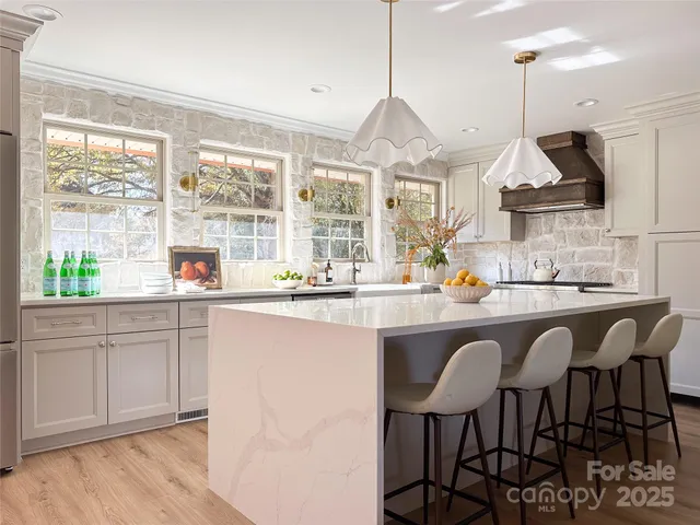 a kitchen with stainless steel appliances granite countertop white cabinets a stove a sink and a chairs