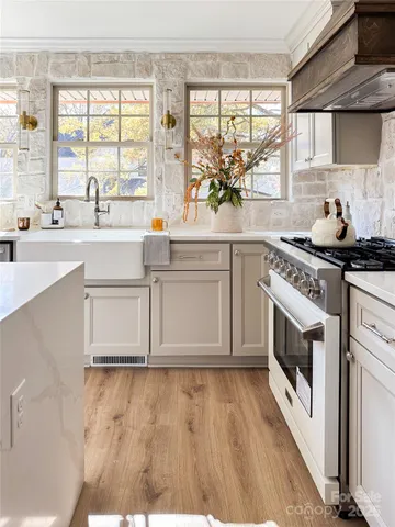 a kitchen with stainless steel appliances a stove a sink and white cabinets