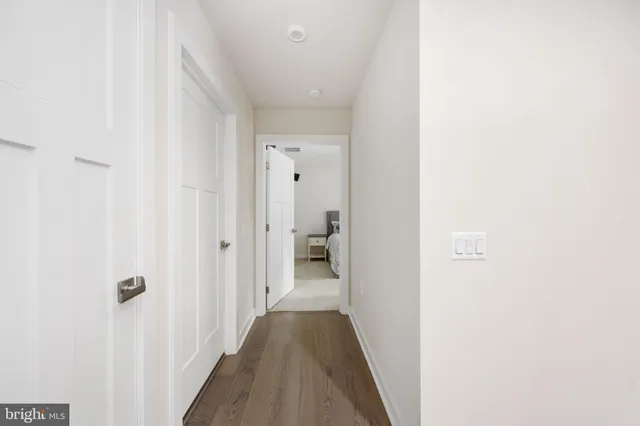 a view of a hallway with wooden floor and a bathroom