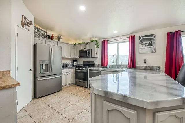 a kitchen with stainless steel appliances granite countertop a refrigerator a stove and a sink