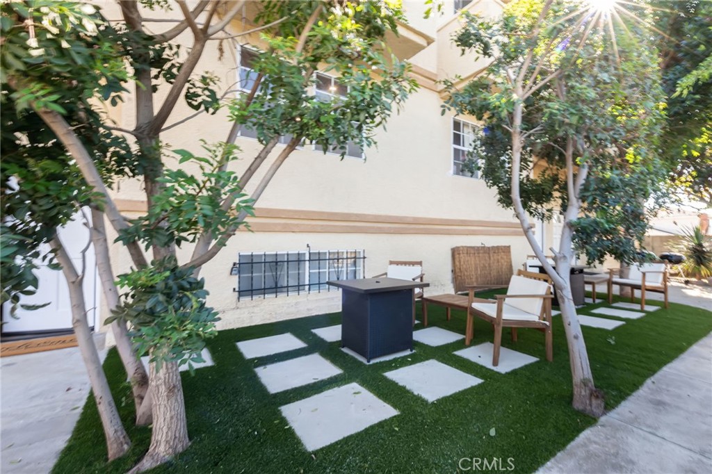 1044 252nd Street, Unit 4 Harbor City, CA 90710 - Photo 4 of 41 a view of backyard with table and chairs potted plants and a large tree